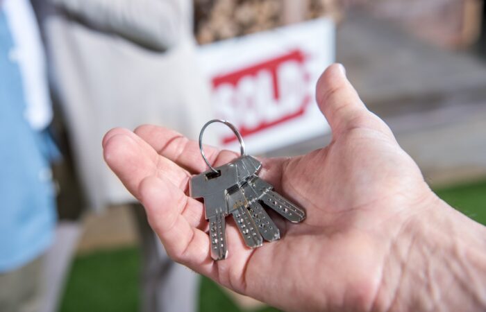 cropped view of saleman holding keys of new house, house for sale concept
